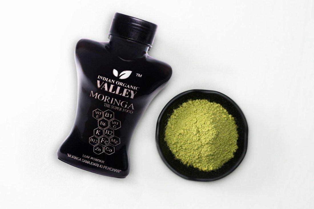 Indian Organic Valley Moringa Leaf Powder bottle with fresh moringa powder